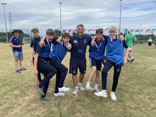 Four male students are seen posing for a photo with a member of staff on Sports Day.